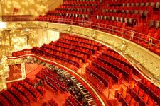 Interior view of Mogador Theatre in Paris with its red seats and golden balconies, ready to host a performance.