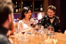 Groupe d’amis partageant une dégustation de vins dans une cave parisienne, ambiance chaleureuse et authentique.